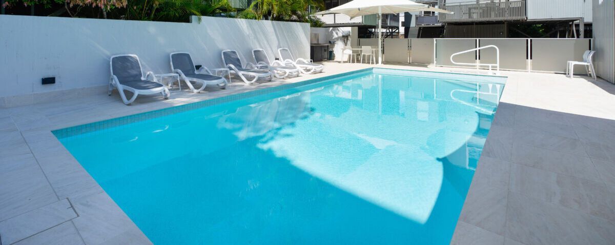 A Rectangular Swimming Pool Surrounded by White Stone — Mad Pool Interiors and Renovations in Baringa, QLD