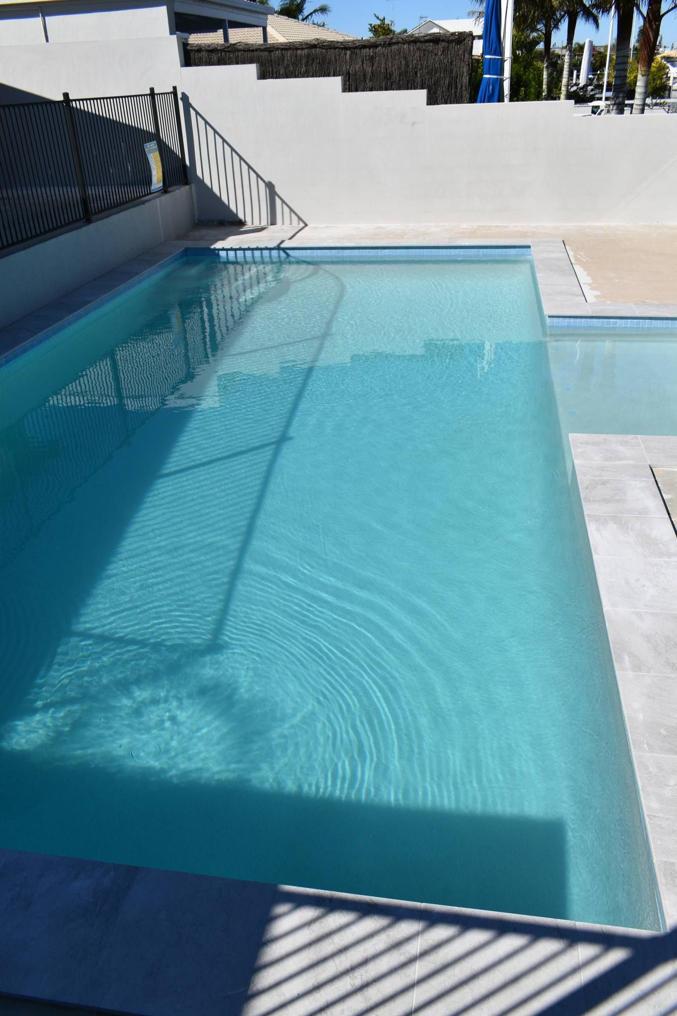 A Clear, Blue Rectangular Swimming Pool With Light Gray Paving Stones — Mad Pool Interiors and Renovations in Baringa, QLD