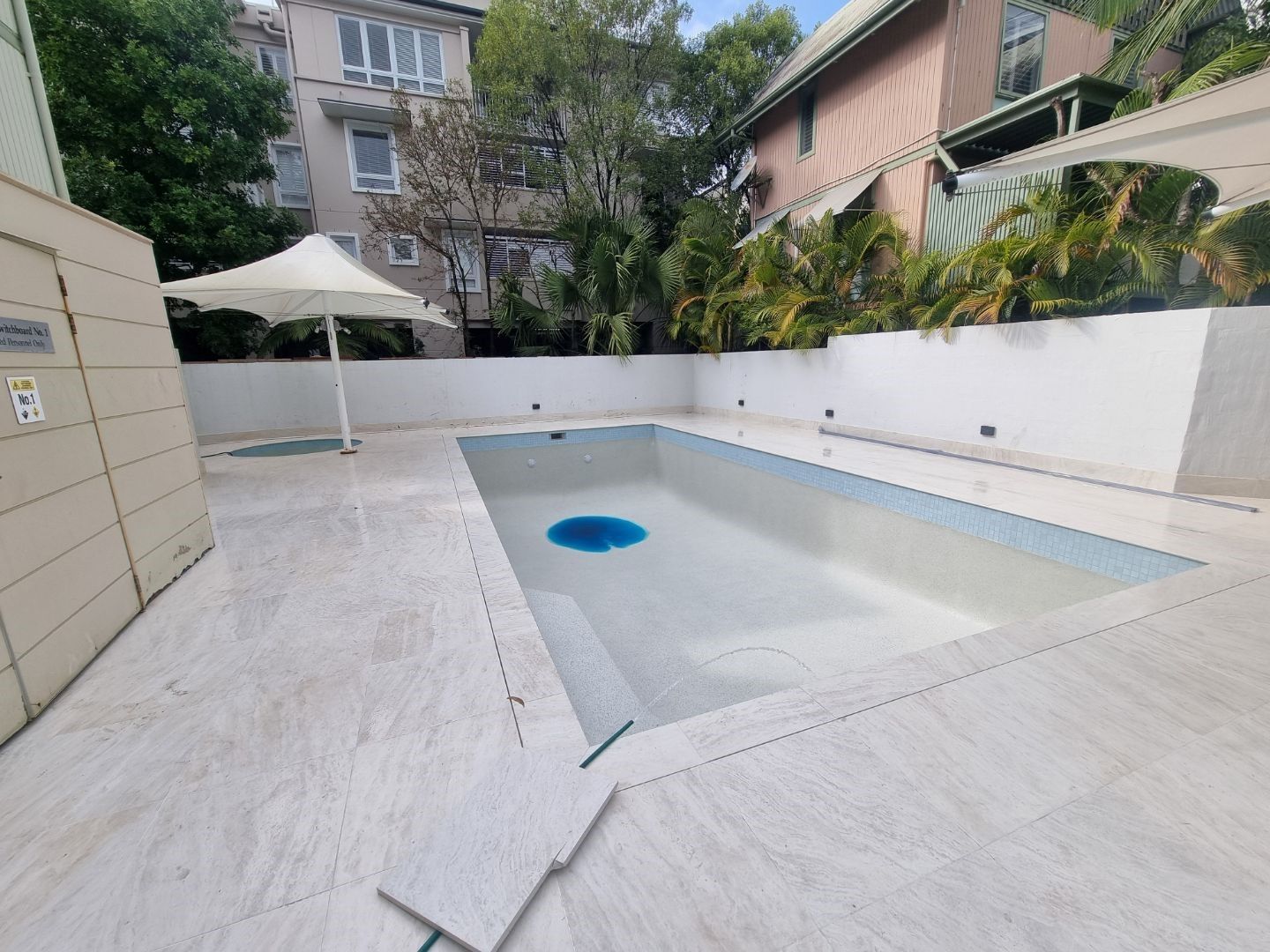 Empty Rectangular Pool With White Stone Surrounds, a White Umbrella — Mad Pool Interiors and Renovations in Baringa, QLD