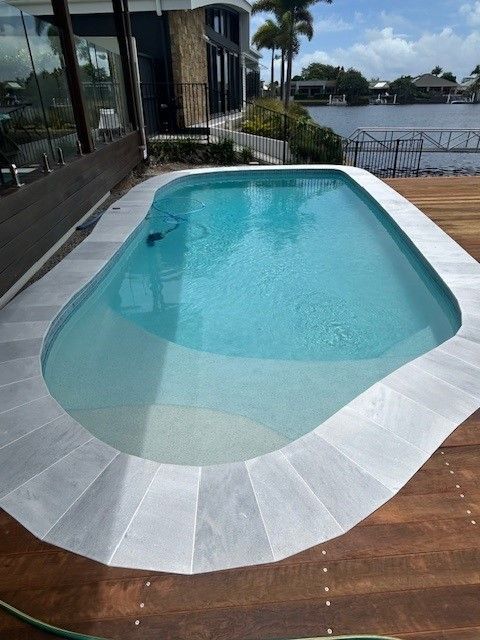 Swimming Pool With Light Blue Water and Stone Border — Mad Pool Interiors and Renovations in Baringa, QLD