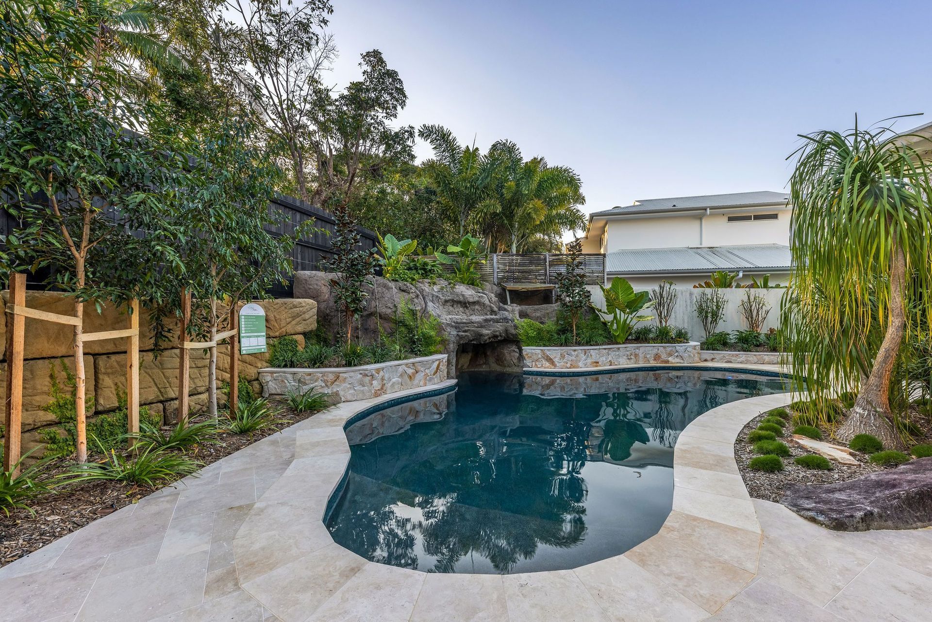 Pool with stone surround and lush landscaping — Mad Pool Interiors and Renovations in Baringa, QLD