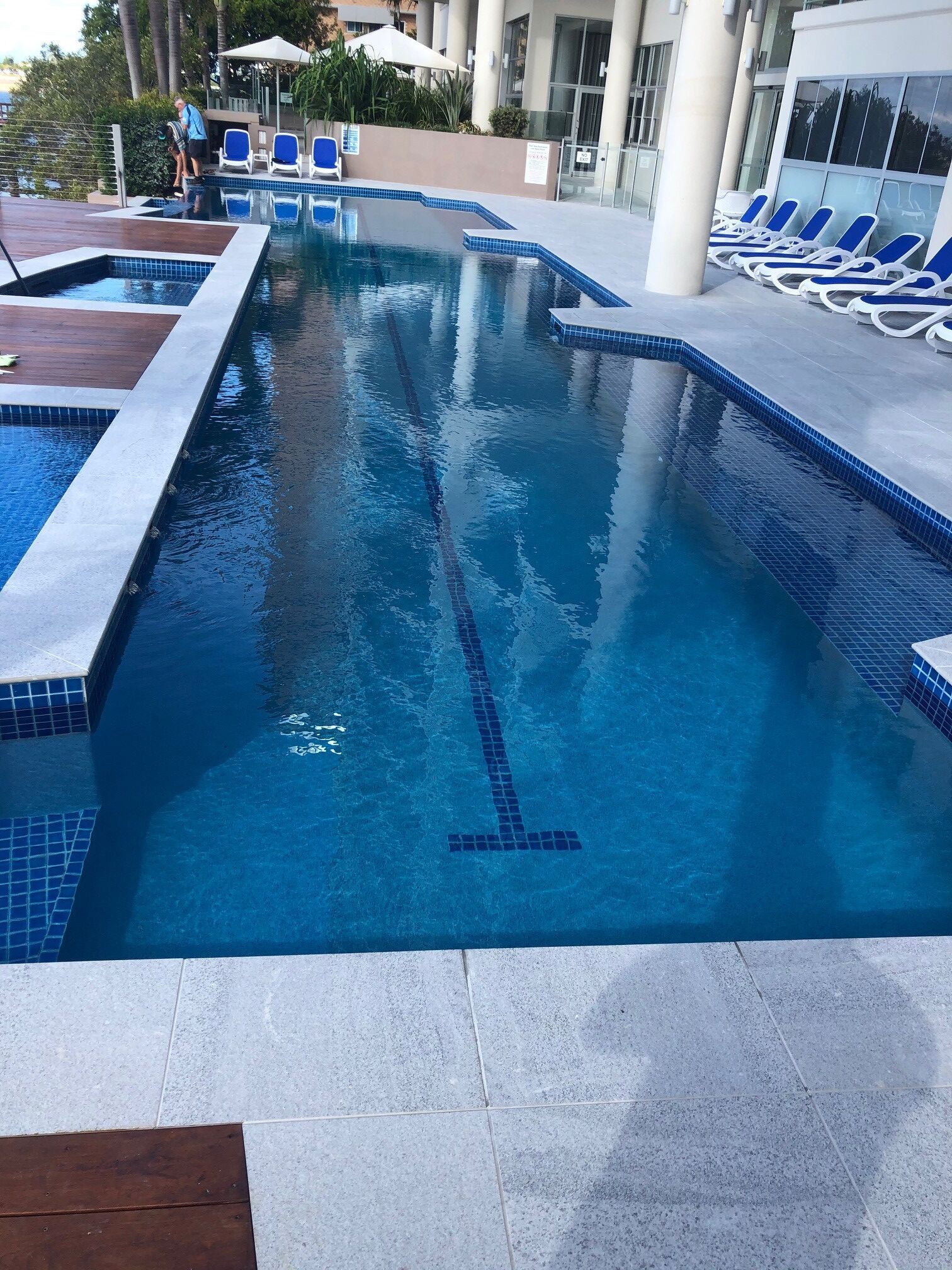 Outdoor Swimming Pool With Blue Lounge Chairs — Mad Pool Interiors and Renovations in Baringa, QLD