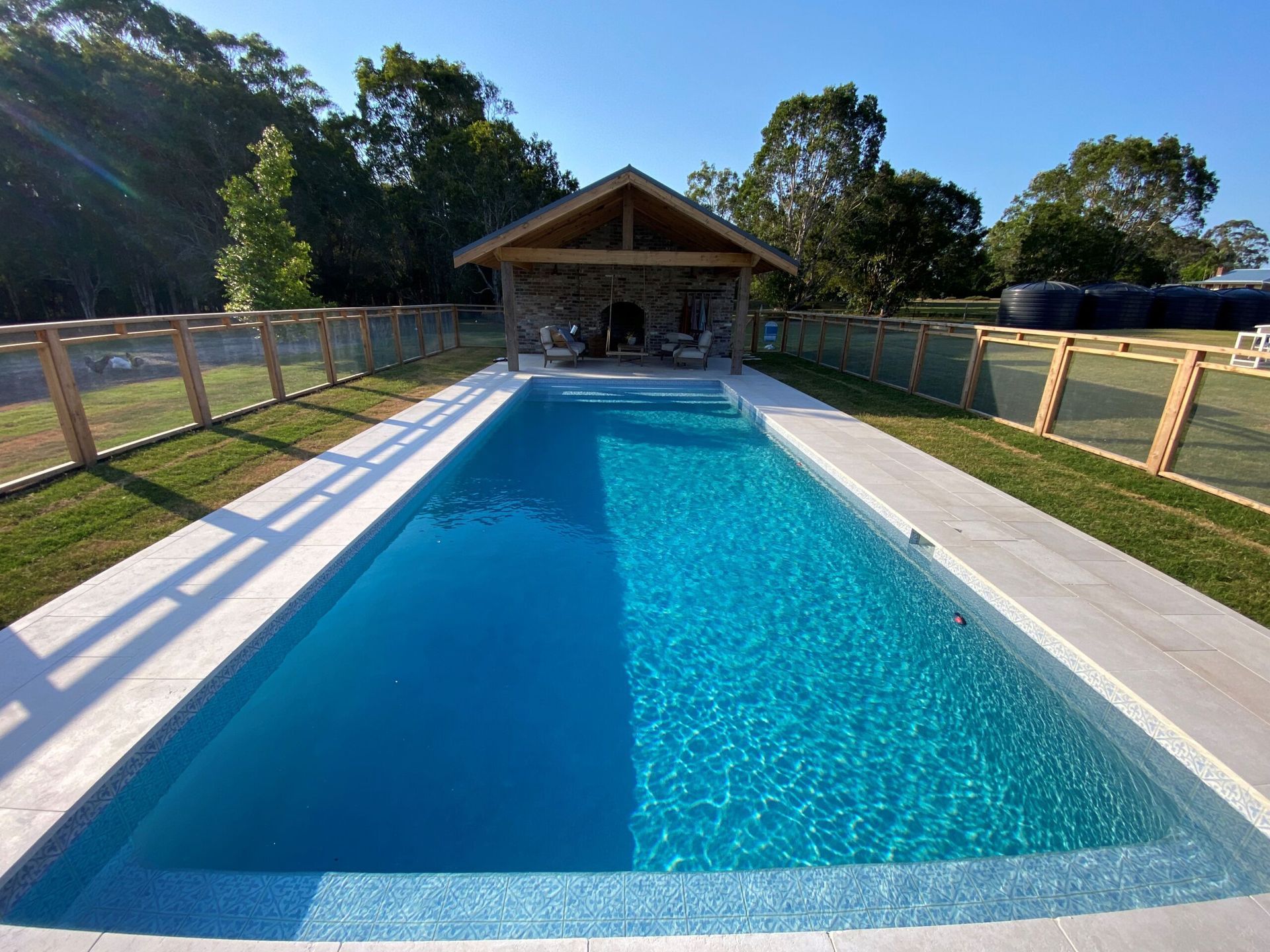 Long Blue Swimming Pool Beside a Wooden Pavilion — Mad Pool Interiors and Renovations in Baringa, QLD