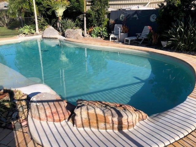 Swimming Pool With Curved Edge, Stone Accents, and Two Lounge Chair — Mad Pool Interiors and Renovations in Baringa, QLD