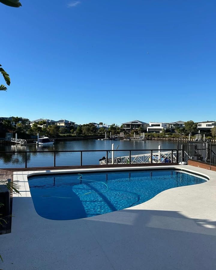 Swimming Pool Overlooking a Body of Water and Houses, Under a Blue Sky — Mad Pool Interiors and Renovations in Baringa, QLD