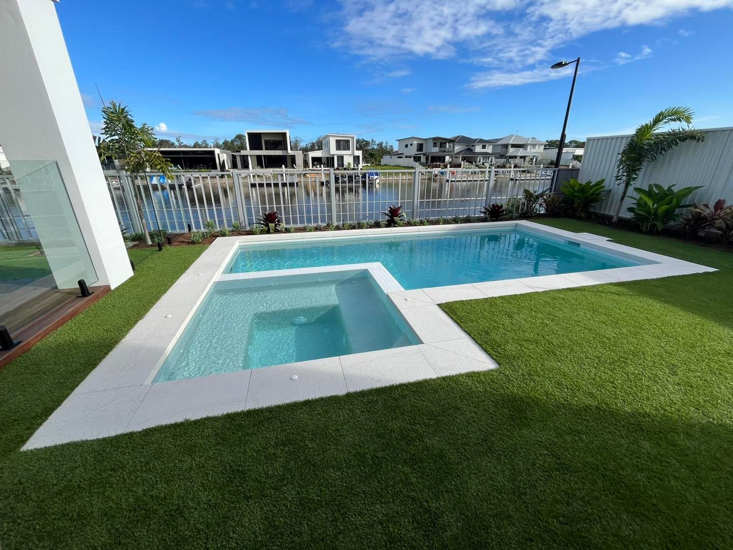 A Modern Pool With Attached Spa, Surrounded by Green Turf — Mad Pool Interiors and Renovations in Baringa, QLD