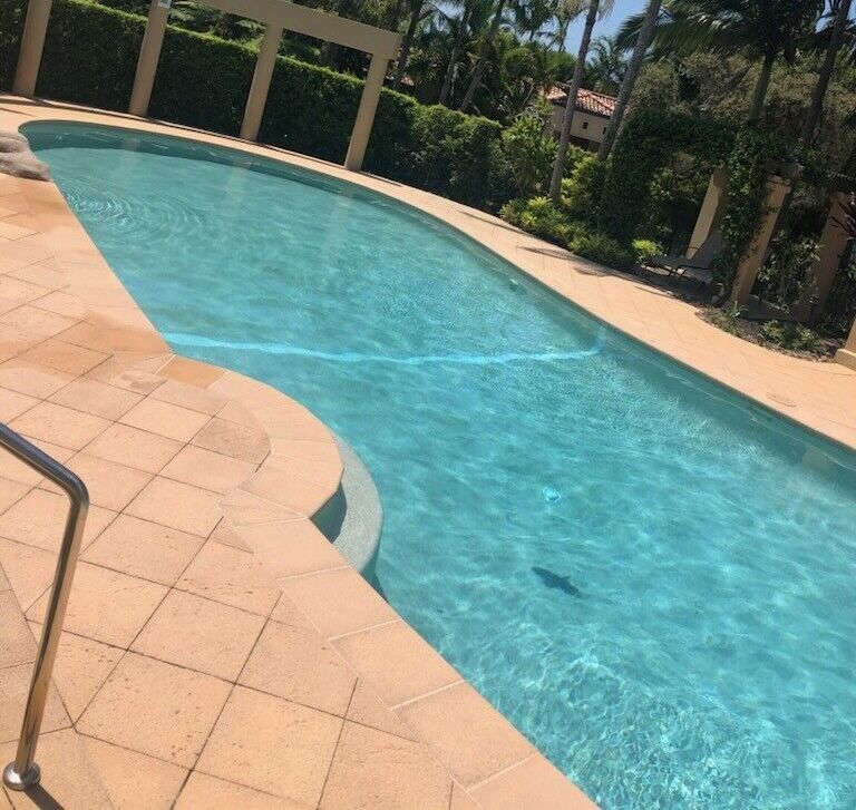 Pool With Clear Blue Water and Tiled Deck in a Sunny Outdoor Setting — Mad Pool Interiors and Renovations in Baringa, QLD