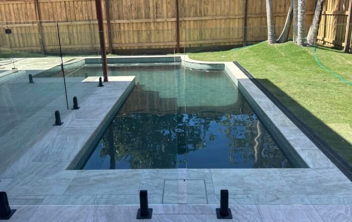 Modern Backyard with A Rectangular Swimming Pool and Light Stone Patio — Mad Pool Interiors and Renovations in Baringa, QLD