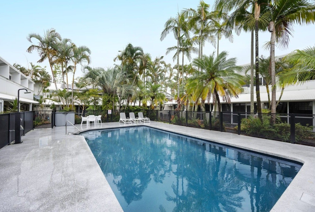 Pool Surrounded by Palm Trees and Low-rise Buildings on a Sunny Day — Mad Pool Interiors and Renovations in Baringa, QLD