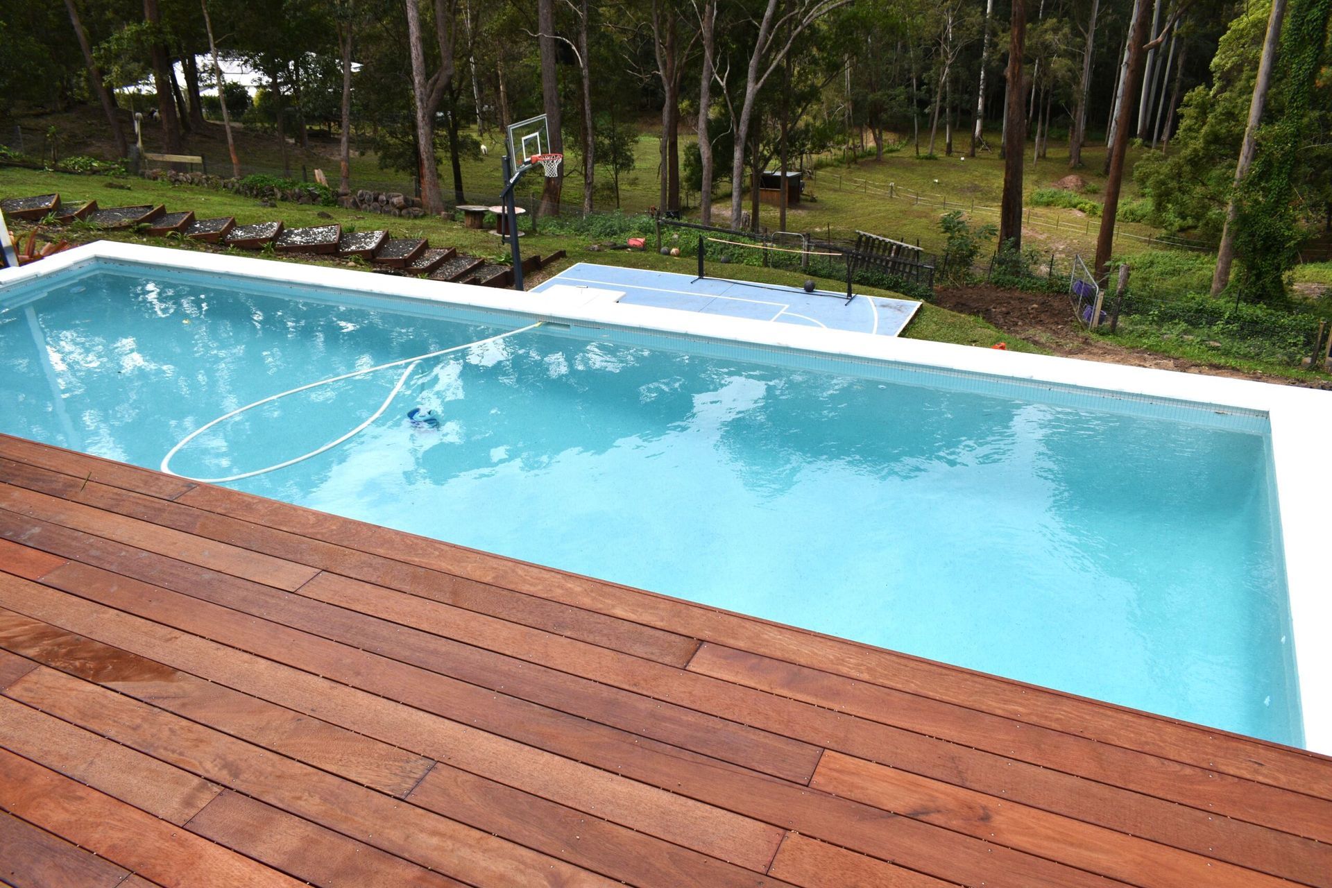 Wooden Deck Overlooking a Rectangular Swimming Pool — Mad Pool Interiors and Renovations in Baringa, QLD