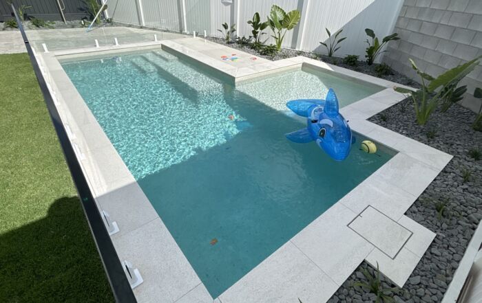 Backyard Pool with Turquoise Water and A Blue Inflatable Float — Mad Pool Interiors and Renovations in Baringa, QLD
