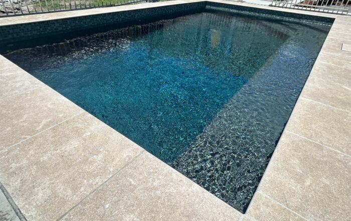 Modern Rectangular Swimming Pool with Blue Water and Beige Stone Paving — Mad Pool Interiors and Renovations in Baringa, QLD