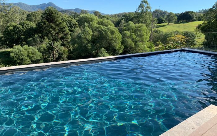 Infinity Pool with Blue Water Overlooking Green Hills — Mad Pool Interiors and Renovations in Baringa, QLD