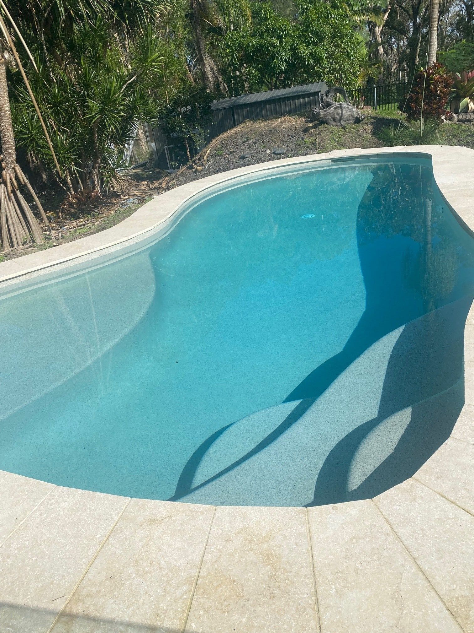 A Blue Swimming Pool With Curved Edges, Surrounded by Tiles — Mad Pool Interiors and Renovations in Baringa, QLD