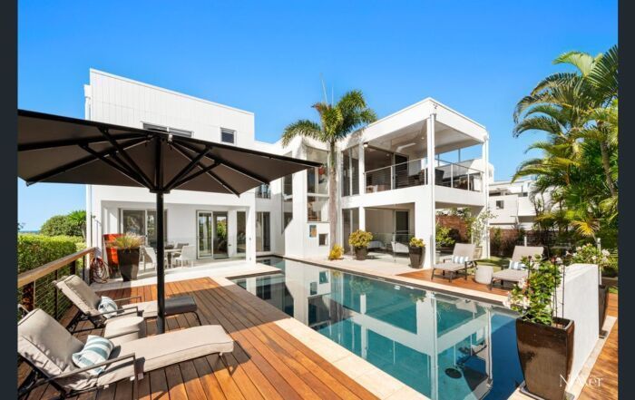 Modern White Villa with Pool, Wooden Deck, Lounge Chairs, and Palm Trees — Mad Pool Interiors and Renovations in Baringa, QLD