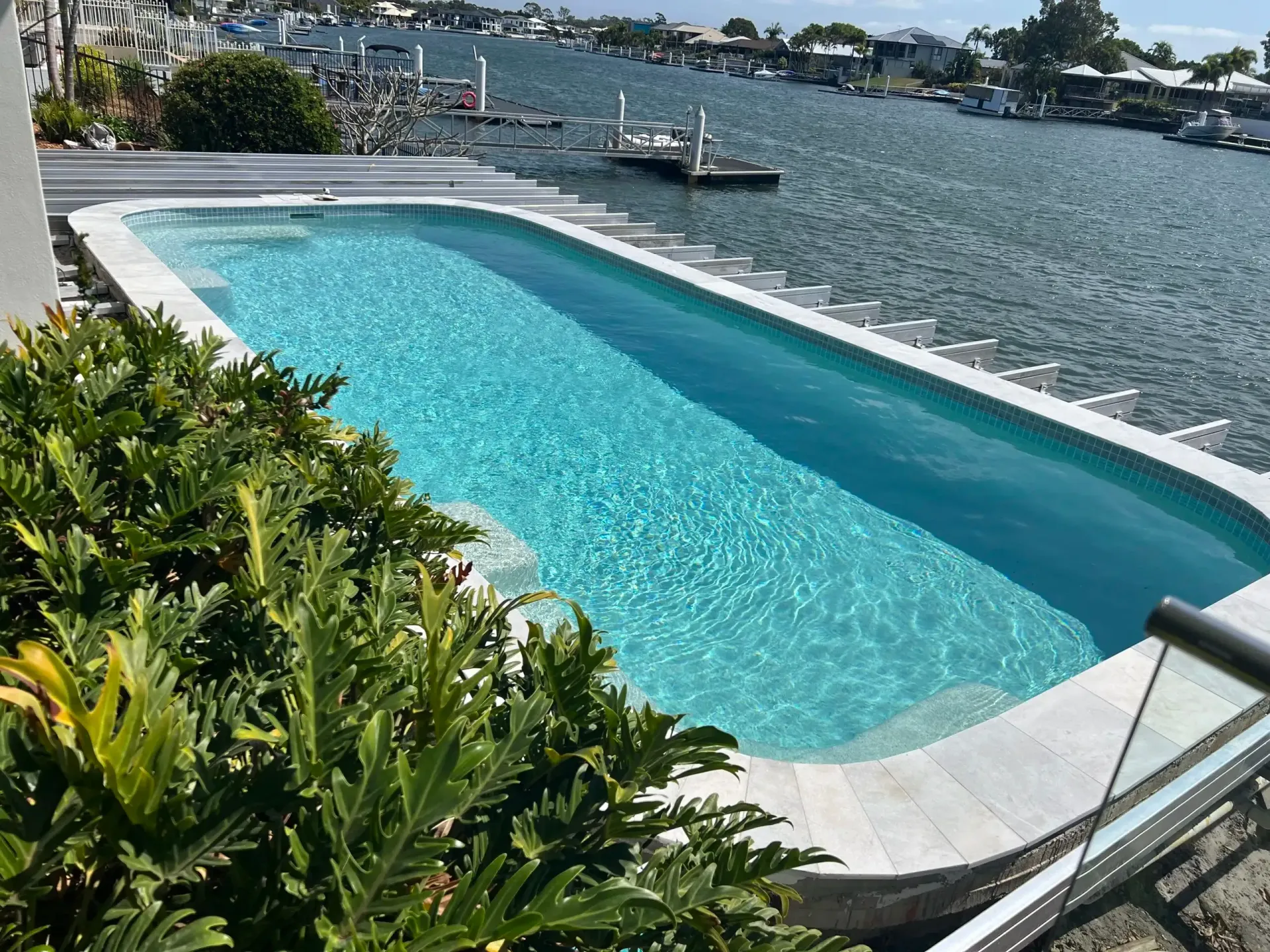 Infinity Pool Overlooking a Harbor, With Turquoise Water and Greenery — Mad Pool Interiors and Renovations in Baringa, QLD