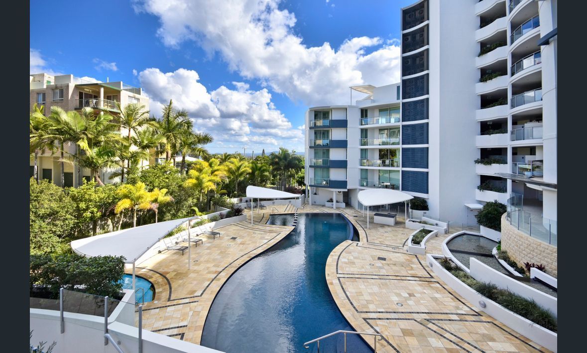 Swimming Pool Between Apartment Buildings With Blue Sky and Clouds — Mad Pool Interiors and Renovations in Baringa, QLD