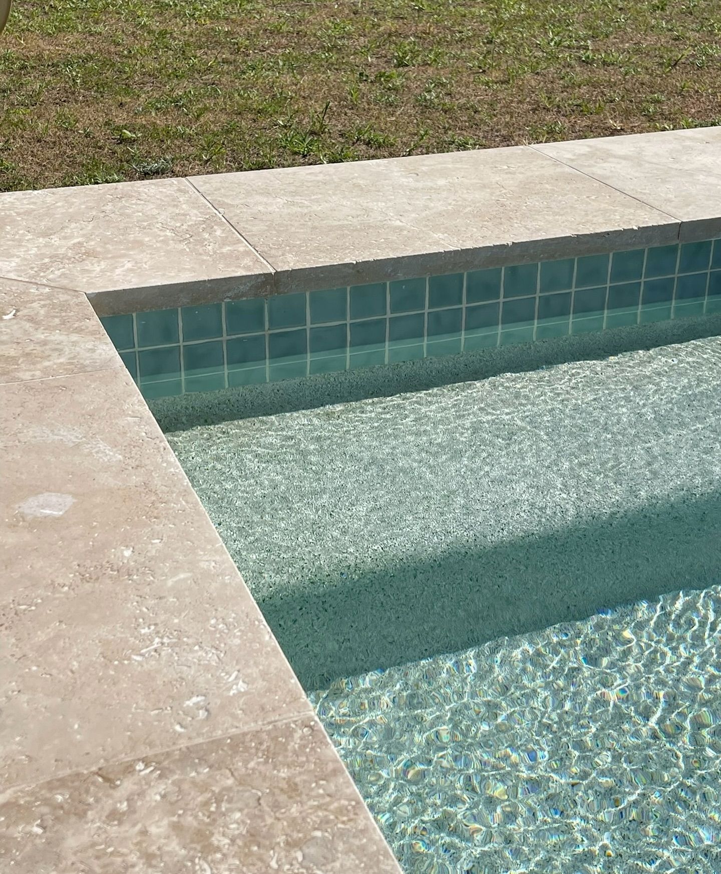 Corner of a Swimming Pool With Light Stone Decking — Mad Pool Interiors and Renovations in Baringa, QLD
