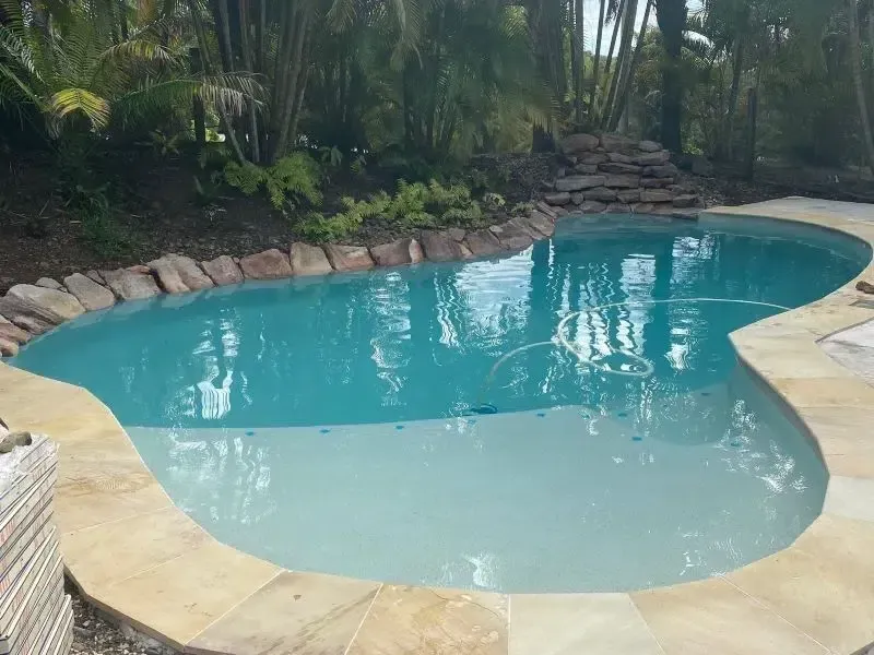 Curved Backyard Swimming Pool With Turquoise Water — Mad Pool Interiors and Renovations in Baringa, QLD