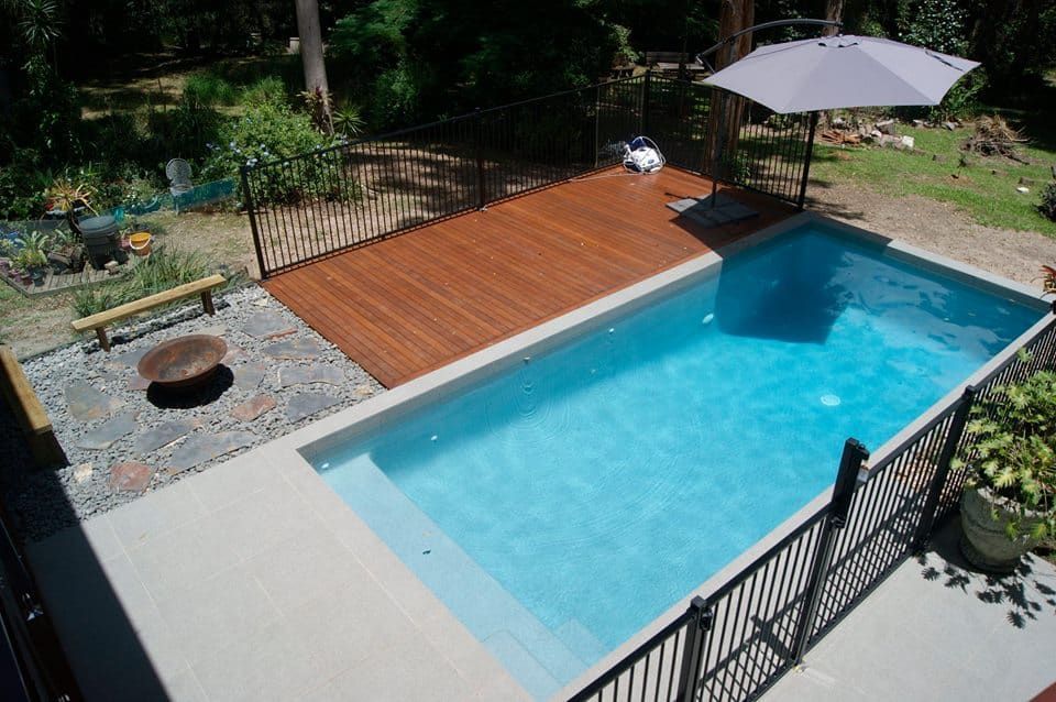 Small Rectangular Pool With Wooden Deck, Black Fence — Mad Pool Interiors and Renovations in Baringa, QLD