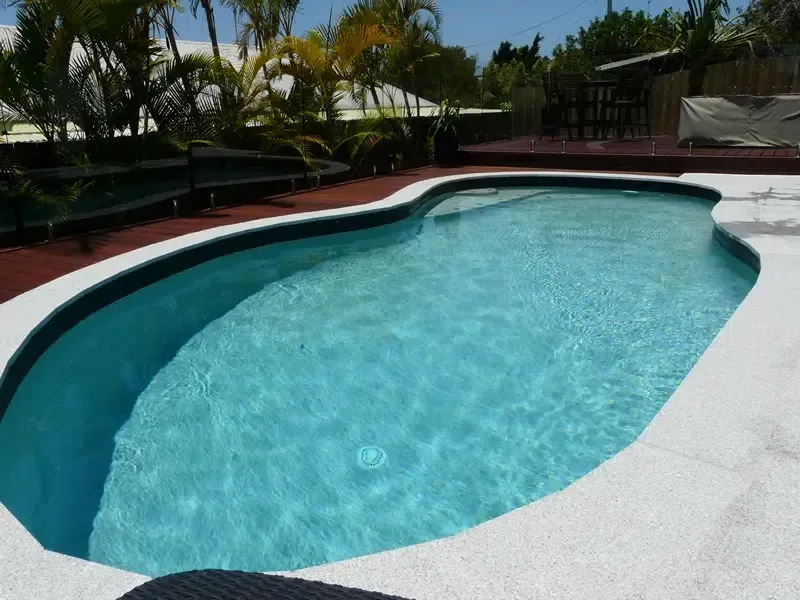 Curved Backyard Swimming Pool With Clear Blue Water — Mad Pool Interiors and Renovations in Baringa, QLD