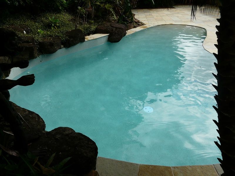 Small Turquoise Pool Surrounded by Tan Stone and Dark Rocks — Mad Pool Interiors and Renovations in Baringa, QLD