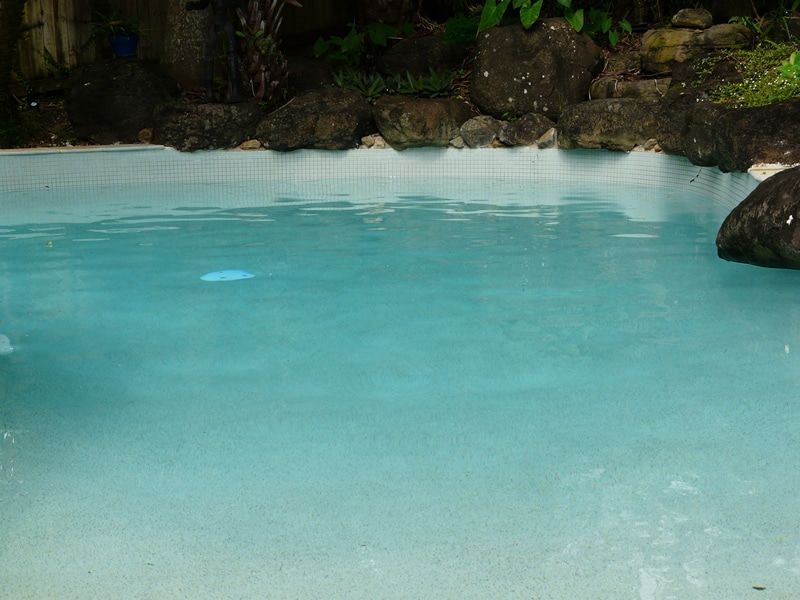 A Clear Blue Swimming Pool With Rocks Along the Edge — Mad Pool Interiors and Renovations in Baringa, QLD