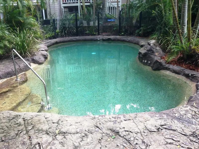 Small Turquoise Backyard Pool Surrounded by Rocks — Mad Pool Interiors and Renovations in Baringa, QLD