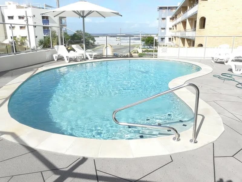 Outdoor Swimming Pool With White Lounge Chairs and Umbrellas — Mad Pool Interiors and Renovations in Baringa, QLD