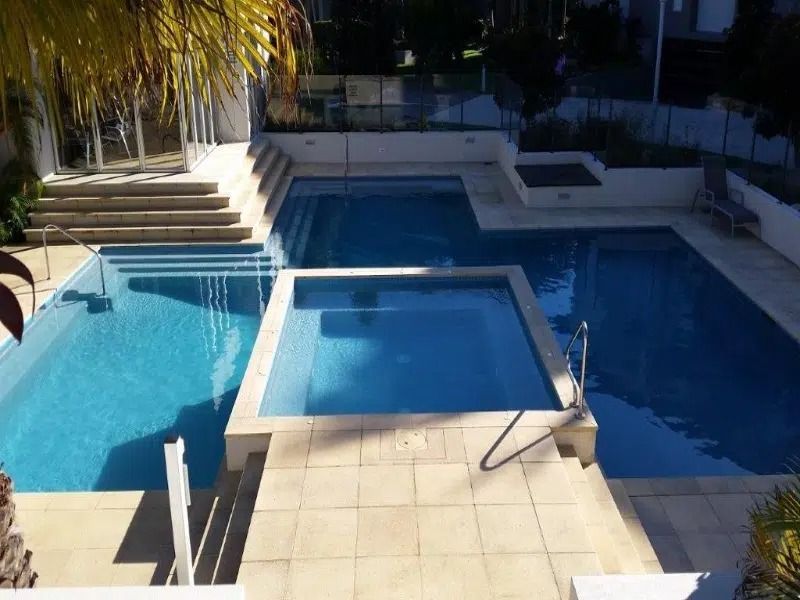 Outdoor Pool Area With a Raised Square Spa in the Center — Mad Pool Interiors and Renovations in Baringa, QLD