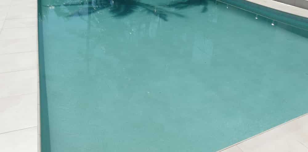 Turquoise Swimming Pool Water Beside a White Tiled Deck — Mad Pool Interiors and Renovations in Baringa, QLD