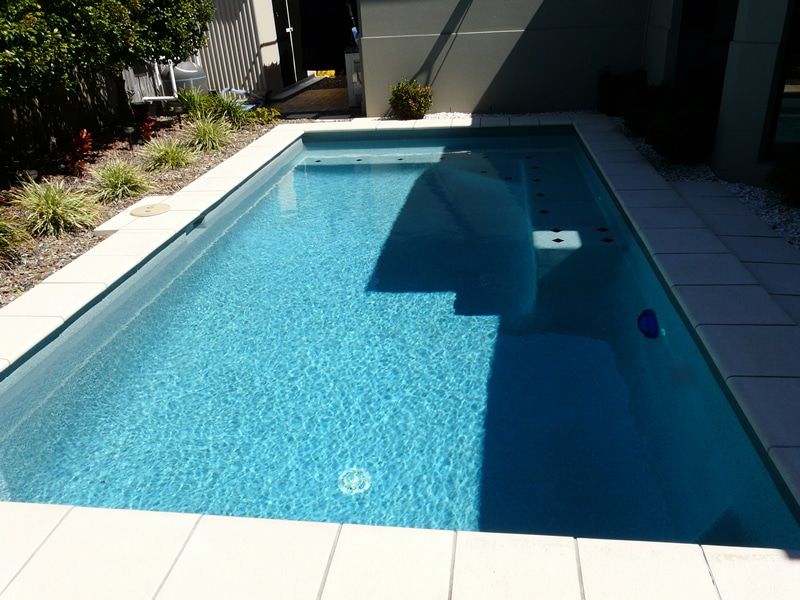 Rectangular Pool With Blue Water, White Tiles, and Small Plants — Mad Pool Interiors and Renovations in Baringa, QLD
