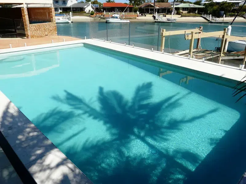 Sunlit Resort Pool With Turquoise Water and Palm Tree Shadows — Mad Pool Interiors and Renovations in Baringa, QLD