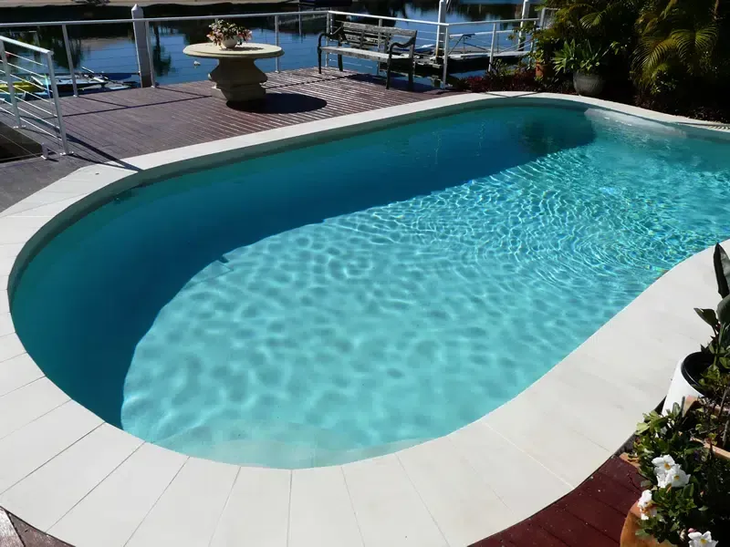 Curved Backyard Swimming Pool With Clear Blue Water — Mad Pool Interiors and Renovations in Baringa, QLD