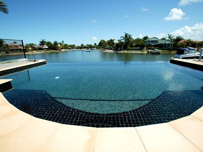 Infinity Pool Overlooking a Waterway With Boats and Houses — Mad Pool Interiors and Renovations in Baringa, QLD