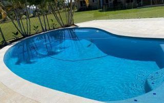 Backyard Swimming Pool with Blue Water and Light Stone Deck in Sunlight — Mad Pool Interiors and Renovations in Baringa, QLD