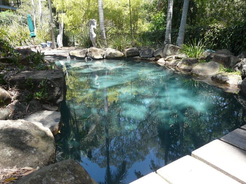 A Tranquil, Turquoise-colored Pond Surrounded by Rocks — Mad Pool Interiors and Renovations in Baringa, QLD