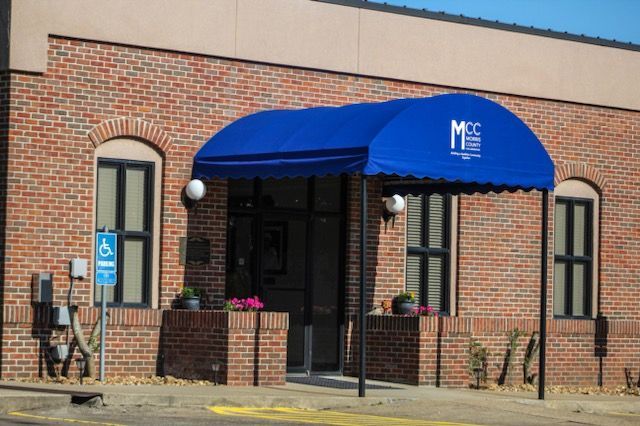 A brick building with a blue awning over the entrance