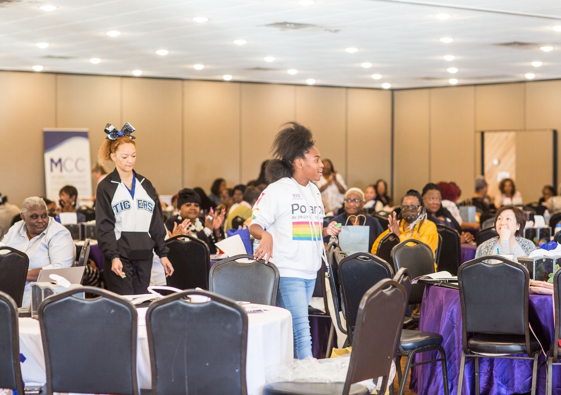 A group of people are sitting at tables in a large room.
