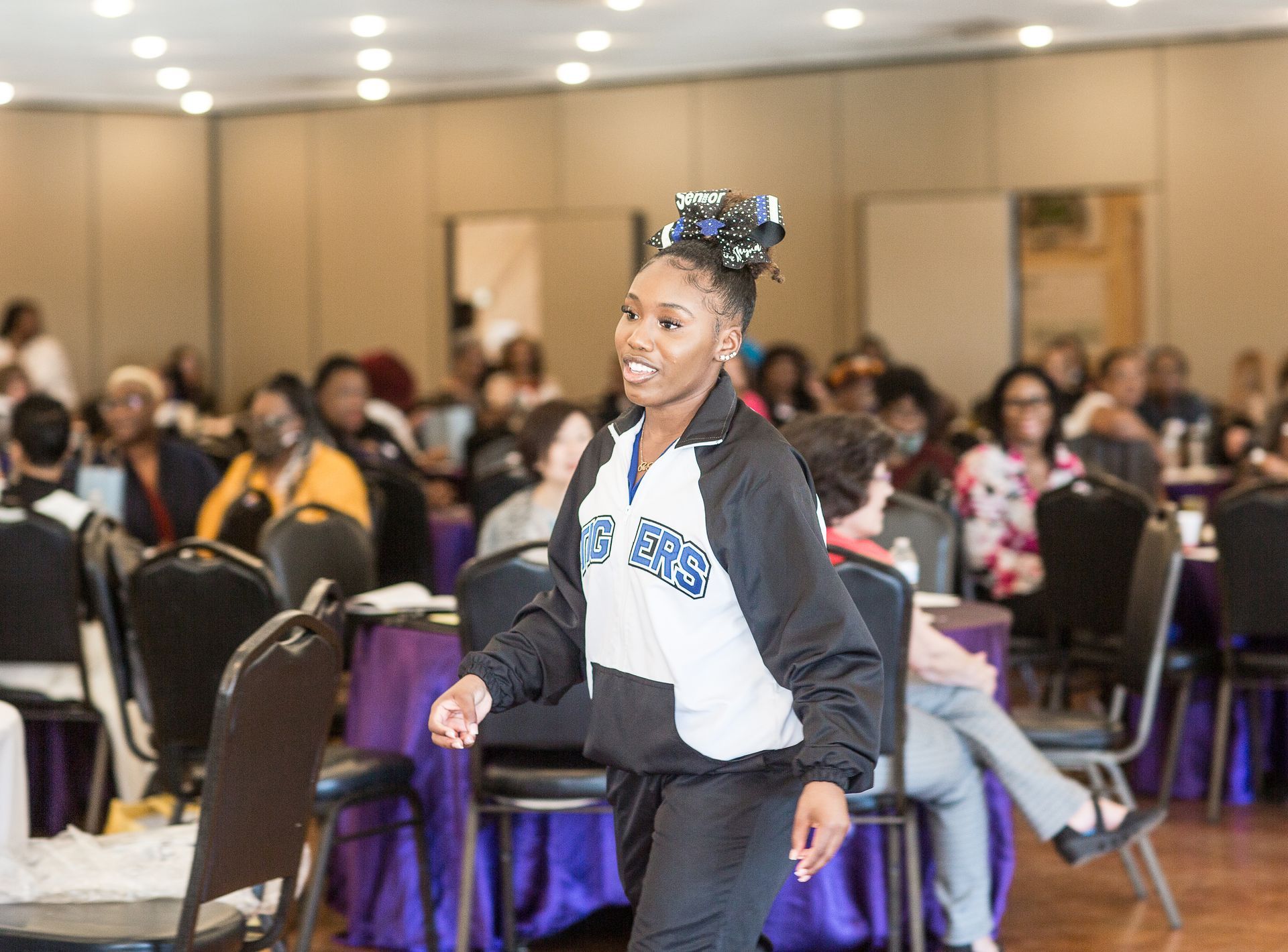 A girl is dancing in a room with tables and chairs.