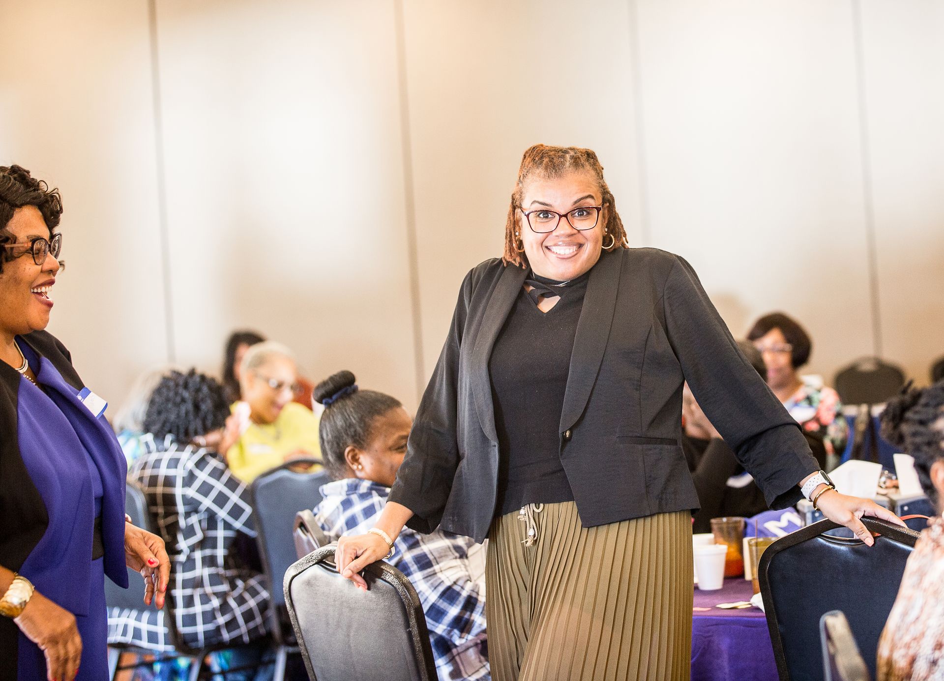 A woman is standing in front of a group of people at a conference.