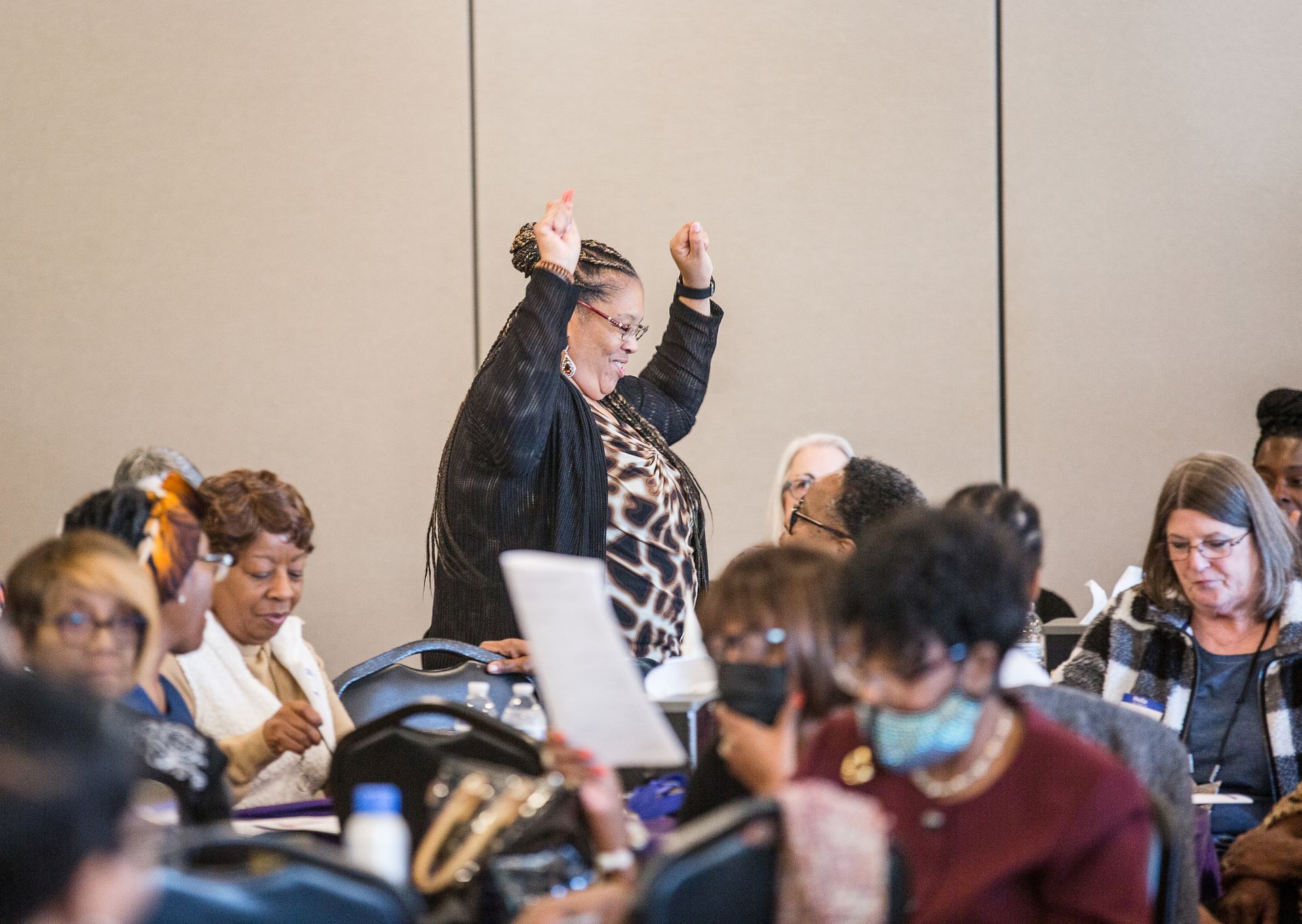 A woman is standing in front of a crowd of people in a conference room.