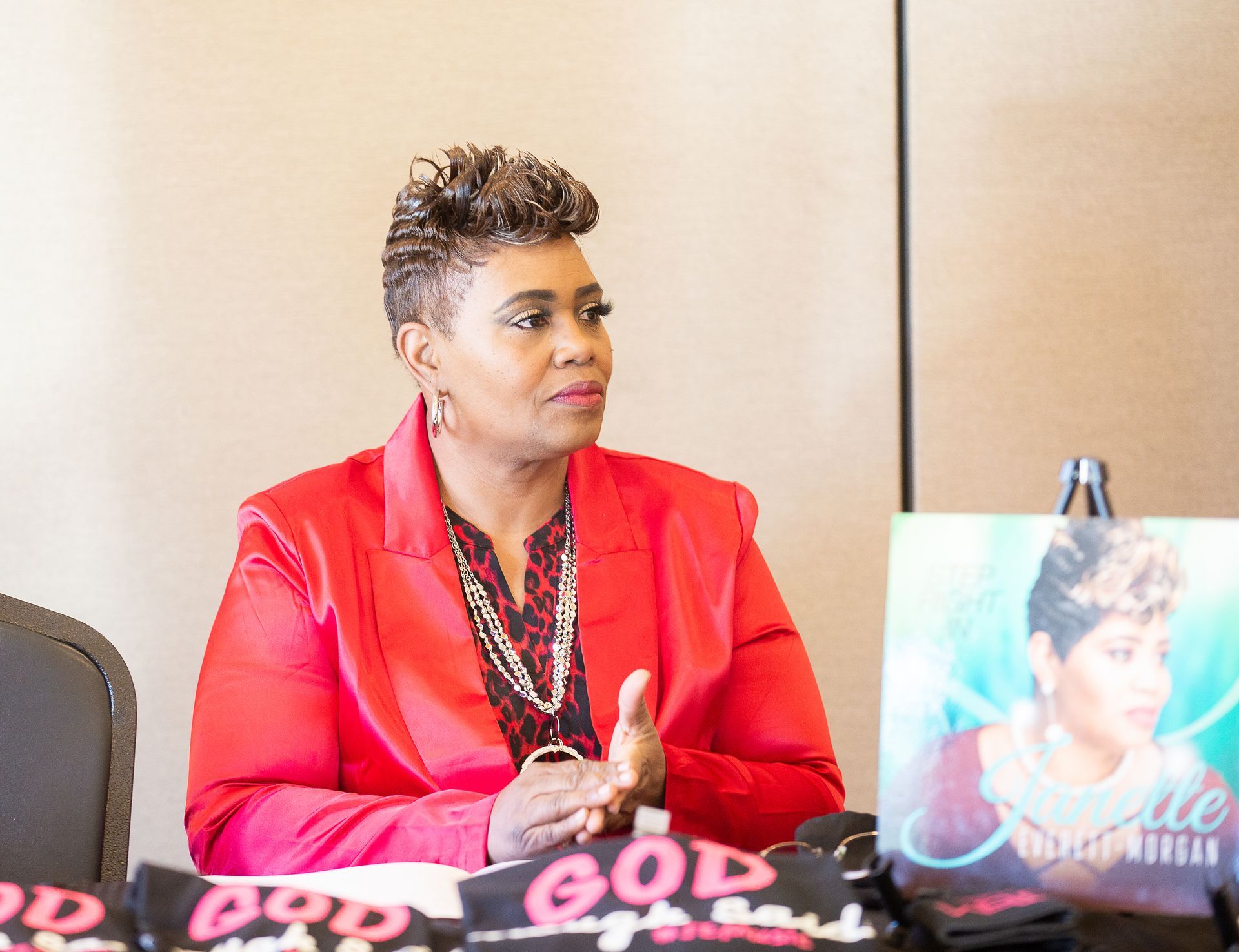 A woman in a red jacket is sitting at a table.