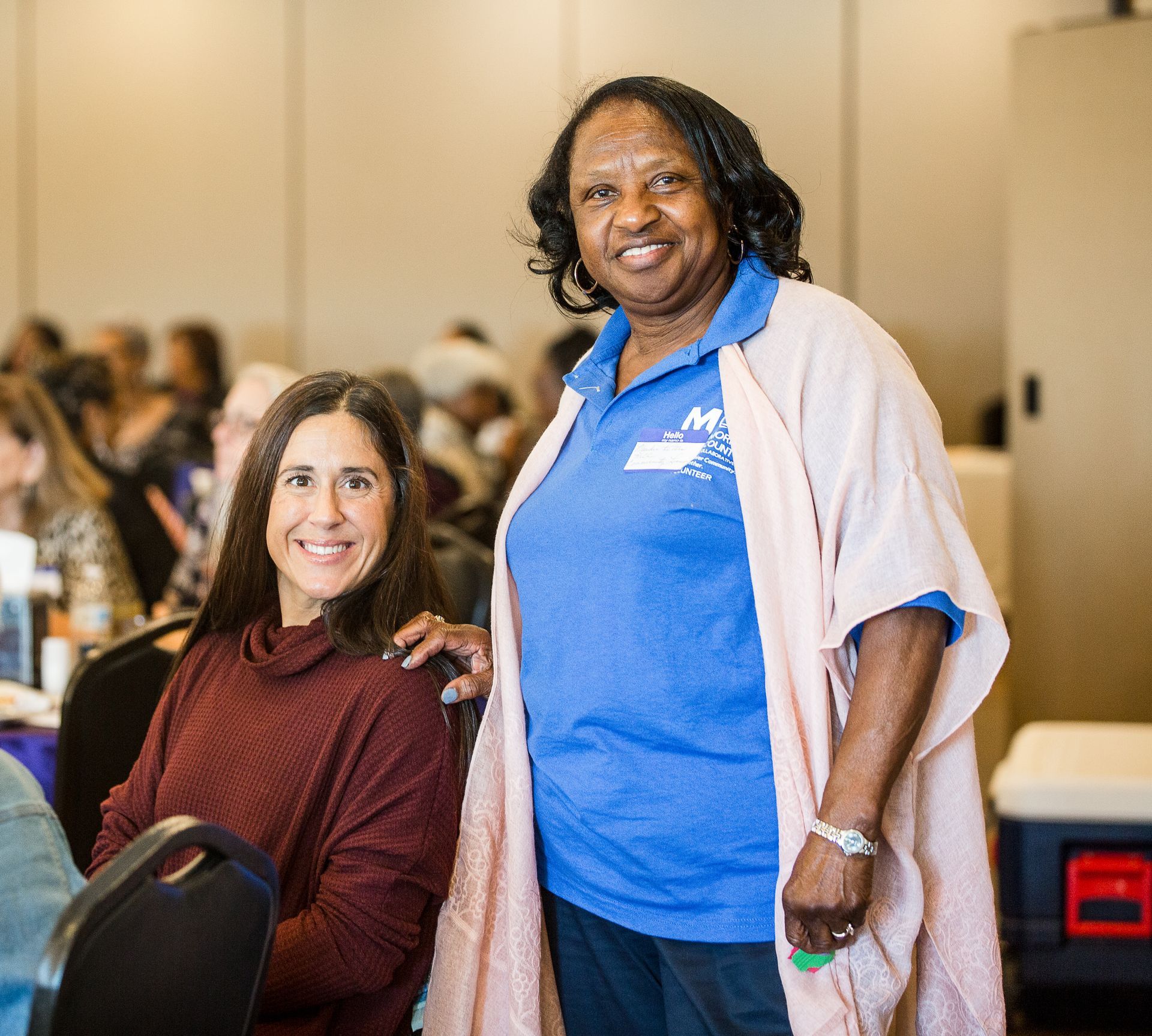 Two women are posing for a picture together in a room.