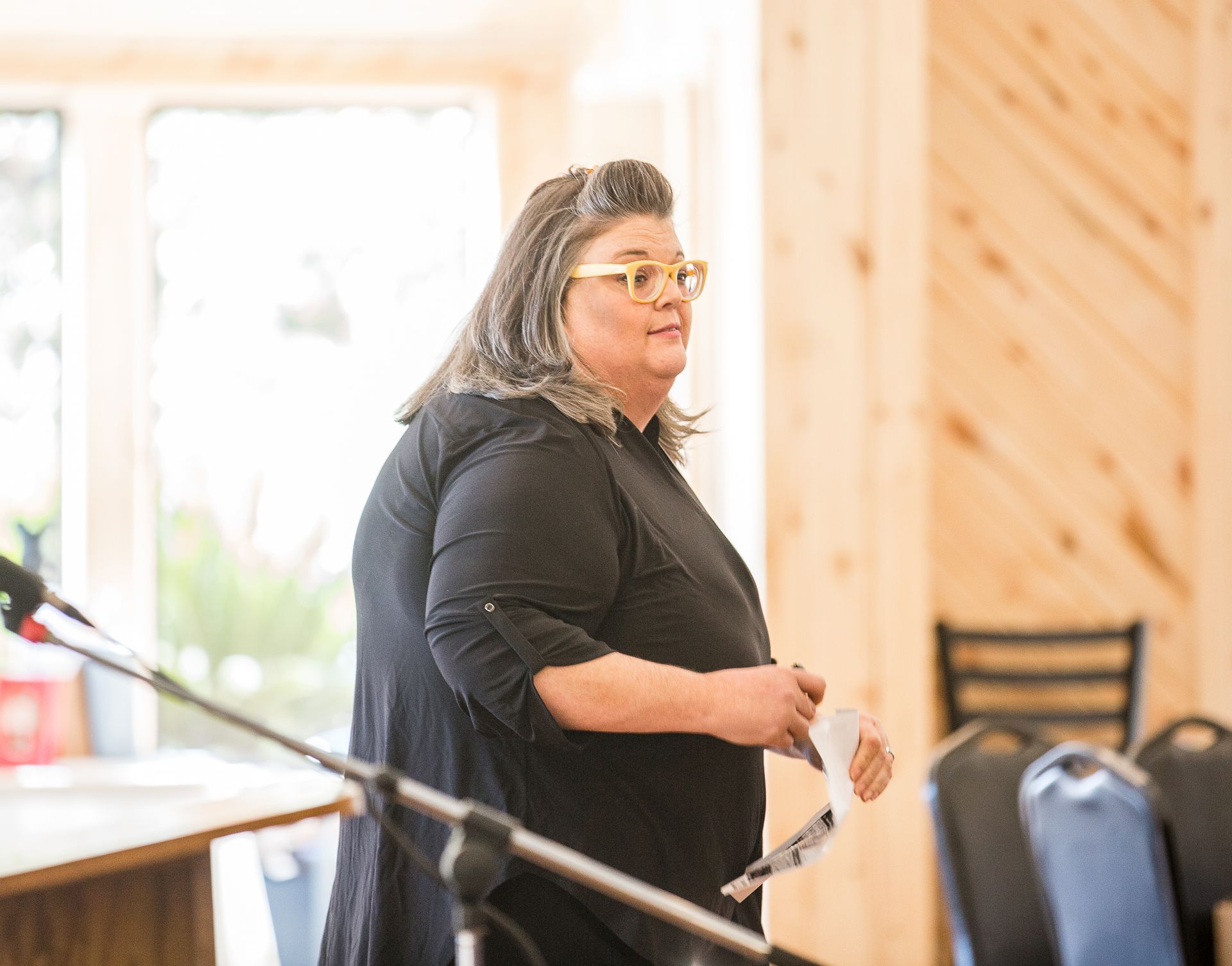 A woman is standing in front of a microphone in a room.