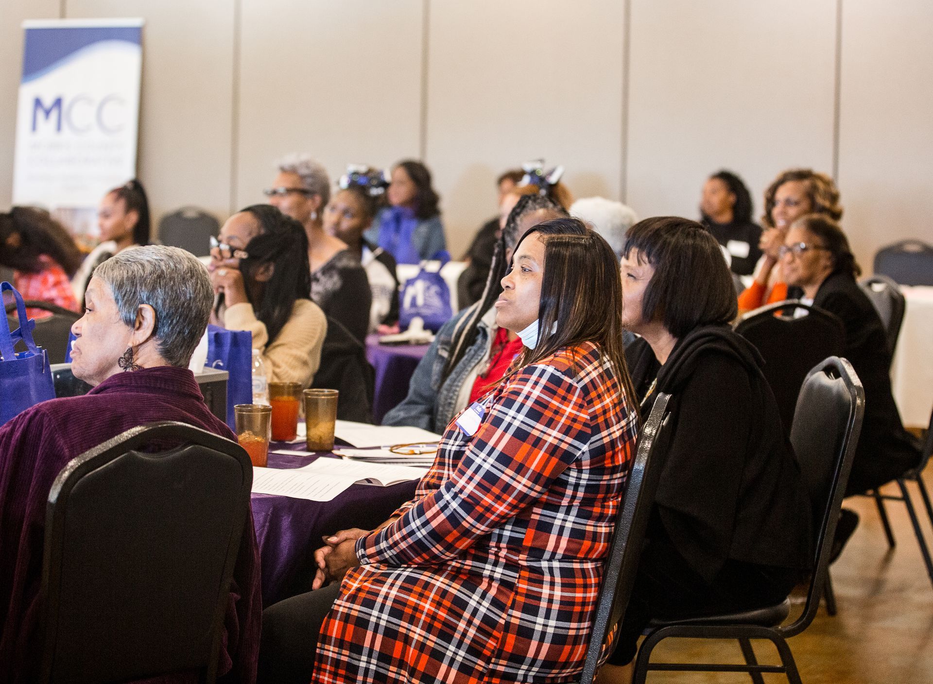 A group of women are sitting at tables in a room.