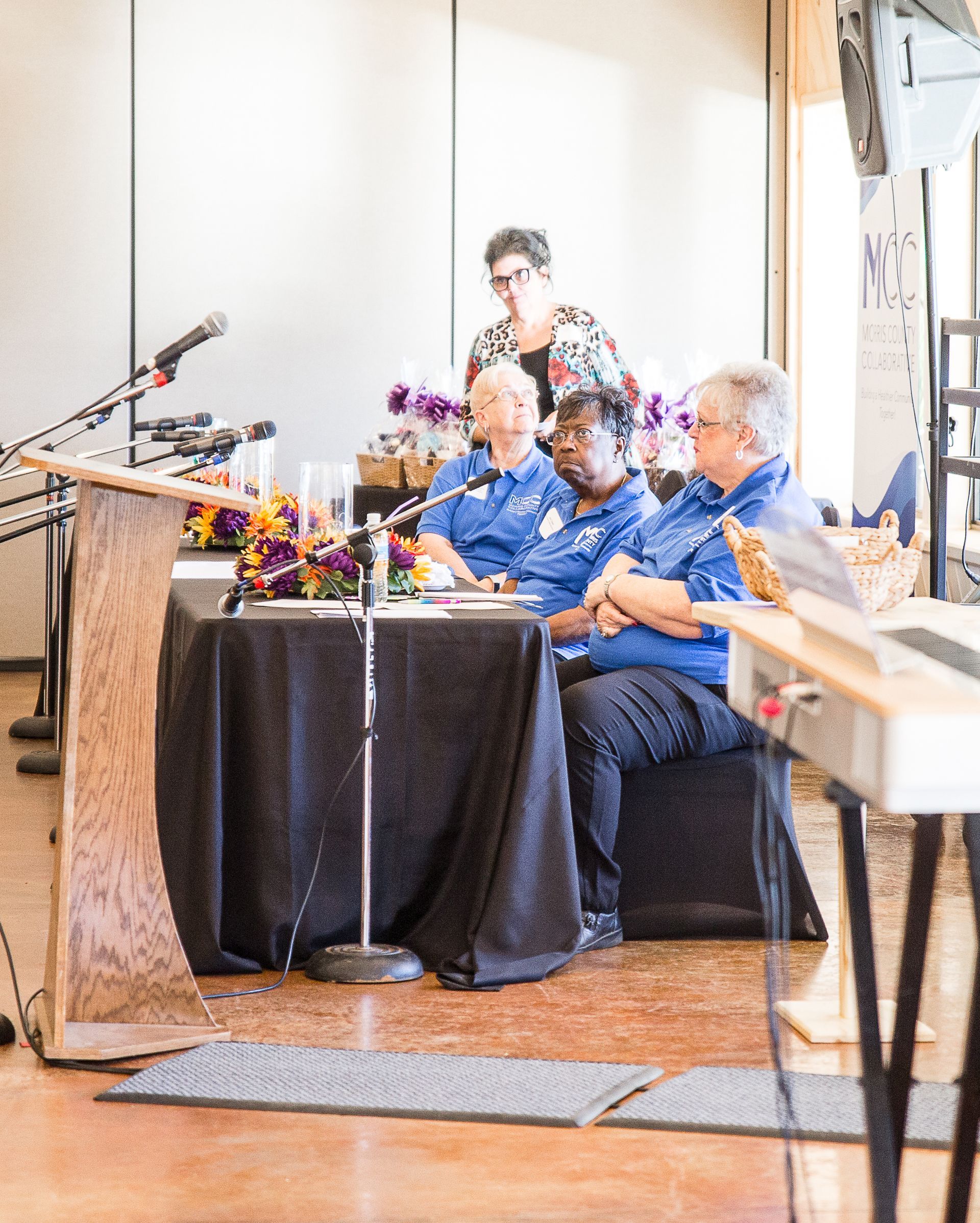 A group of people are sitting at a table in front of microphones.