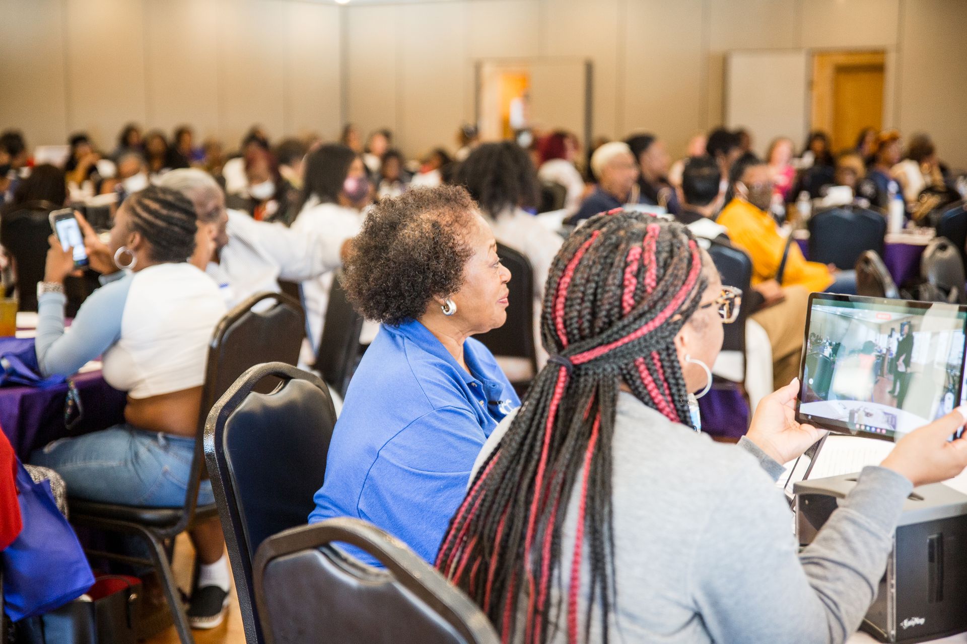A group of people are sitting at tables in a conference room.