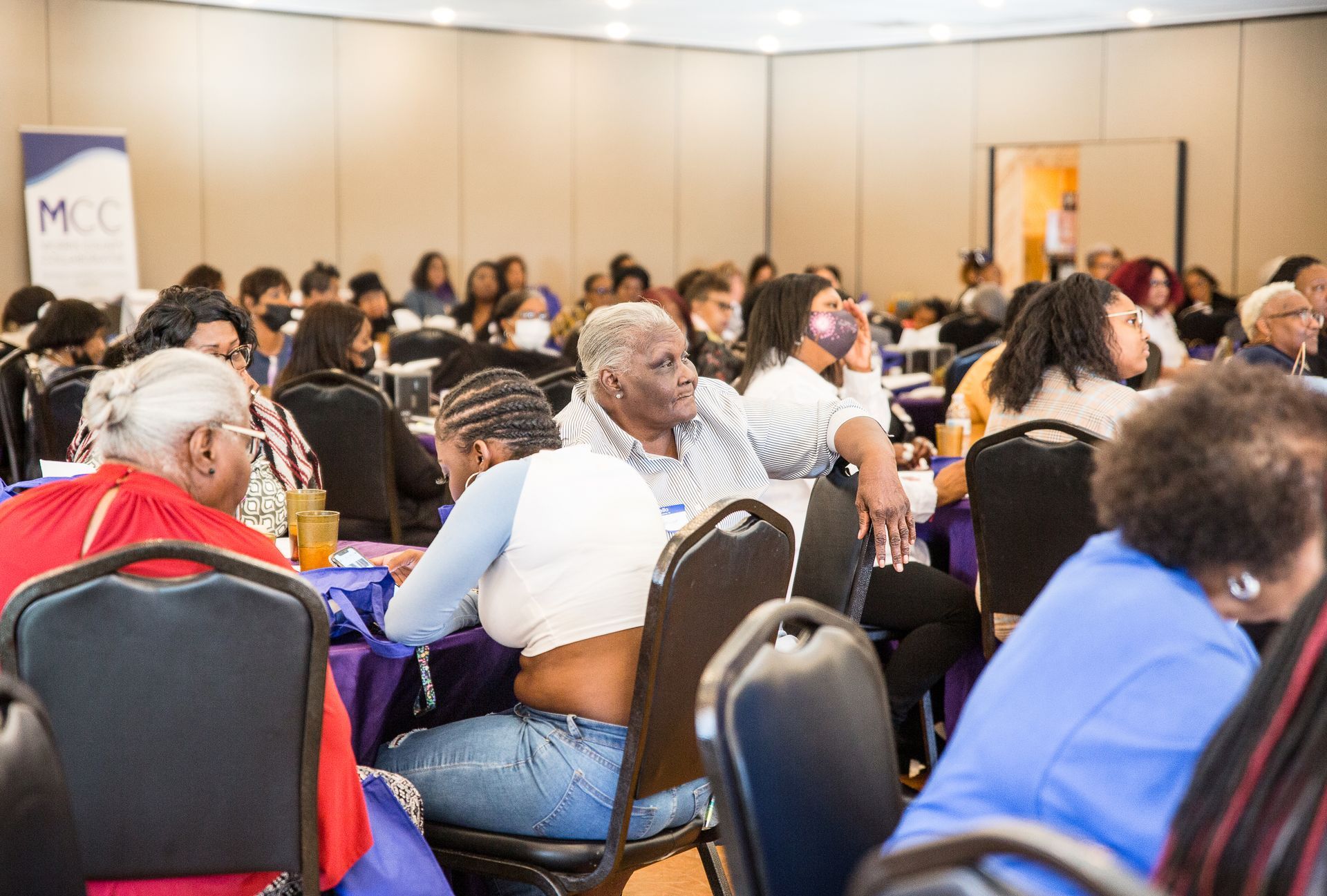 A large group of people are sitting at tables in a room.