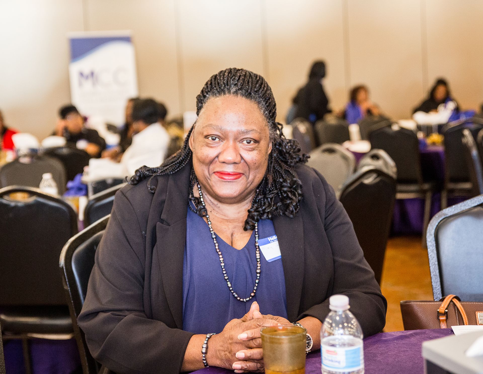 A woman is sitting at a table with a bottle of water.